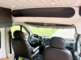 View inside an rv rental camper van: driver's cabin, custom overhead storage, and slatted white ceiling with lights.