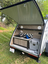 This RV rental features an open teardrop camper's rear kitchen with a sink, cooktop, and K2 cooler, ready for outdoor adventures.