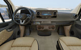 Mercedes-Benz RV interior with modern dash, steering wheel, and tan seats, facing a beach landscape. Perfect for rv rental.