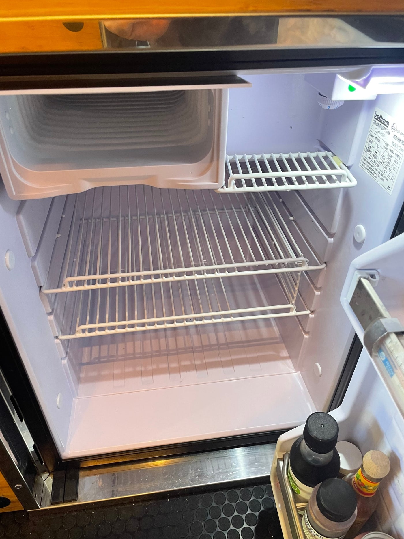 Empty Isotherm RV rental fridge interior with wire shelves & small freezer, ready for food. — photo 7