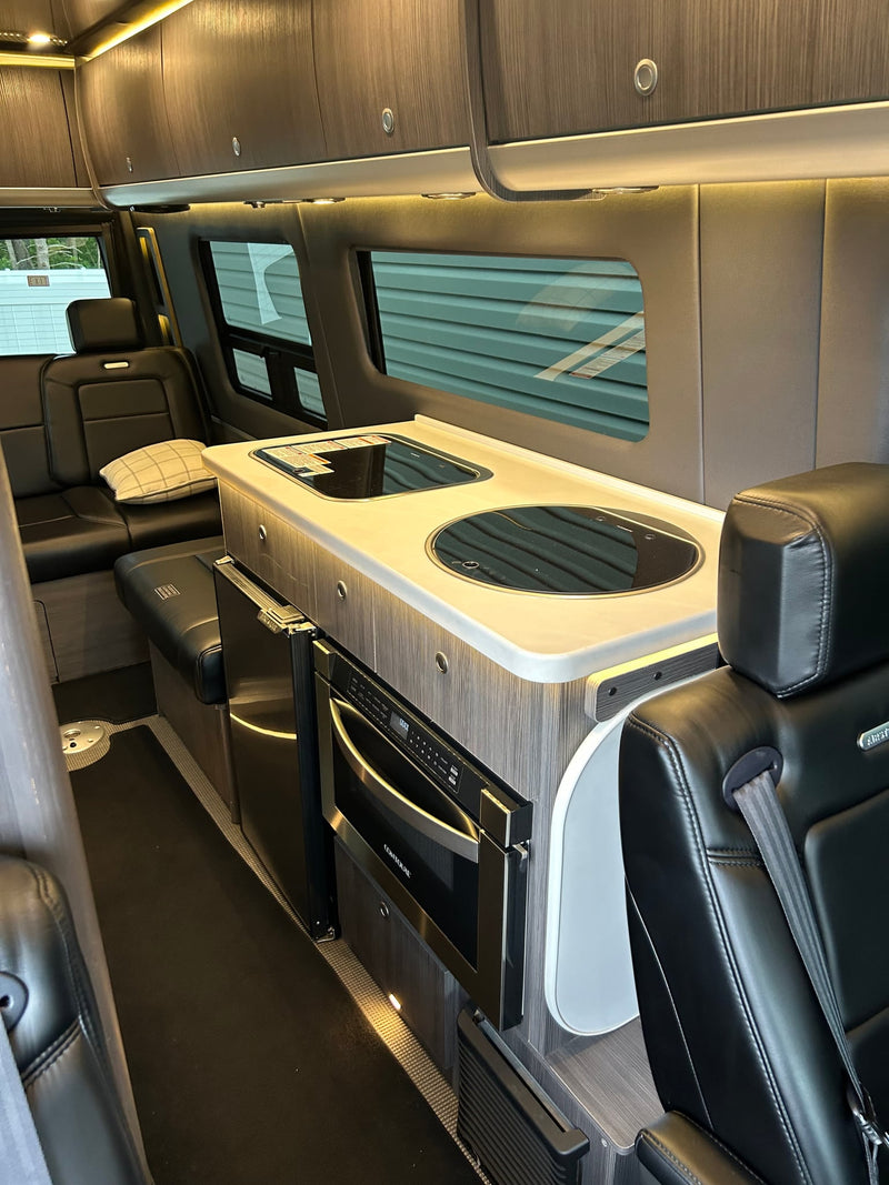  parked beside a house. Ideal luxury camper van.|Luxury rv rental interior: black leather captain's chairs — photo 5