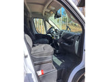Front cabin of an RV rental van, showcasing driver/passenger seats, dashboard, and a visible fire extinguisher.
