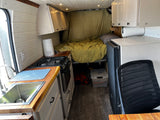 Compact RV rental interior with a fully equipped kitchen, comfortable bed, and smart storage solutions.
