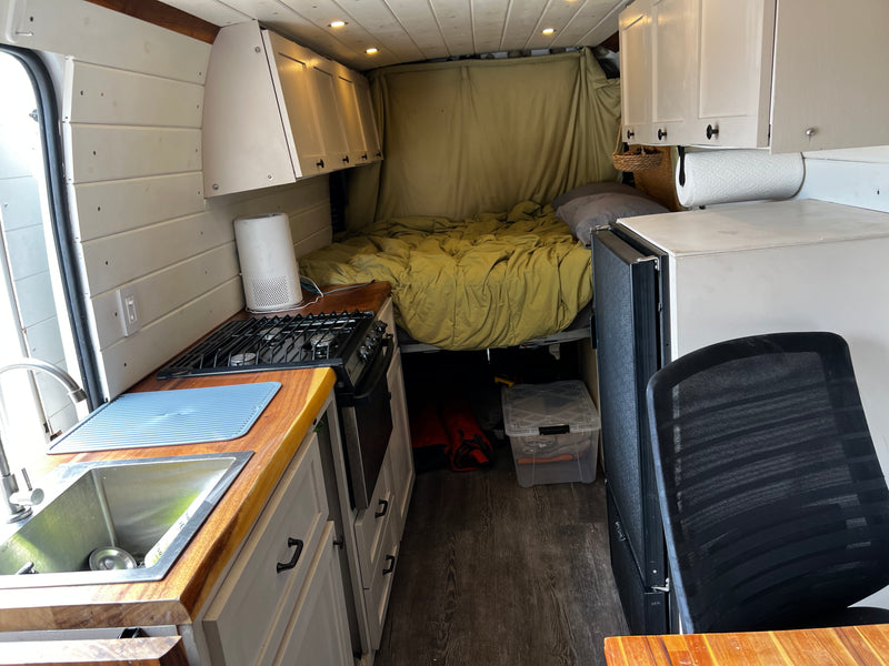 Compact RV rental interior with a fully equipped kitchen, comfortable bed, and smart storage solutions. — photo 15