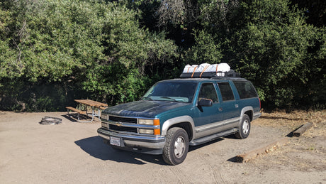 Green Chevy Suburban SUV at a rustic campsite. A practical alternative to an RV rental for your outdoor journey.
