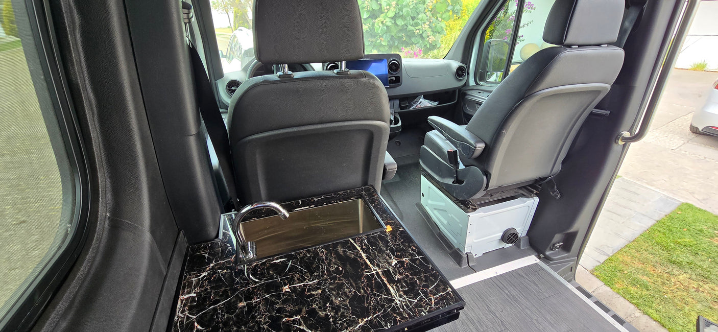 RV rental interior: A compact camper van with a black marble sink and chrome faucet, plus front swivel seats for versatile living.