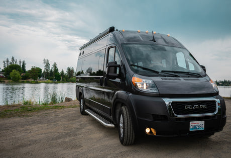 Black Ram ProMaster rv rental van by a serene lake, perfect for your next outdoor travel adventure.