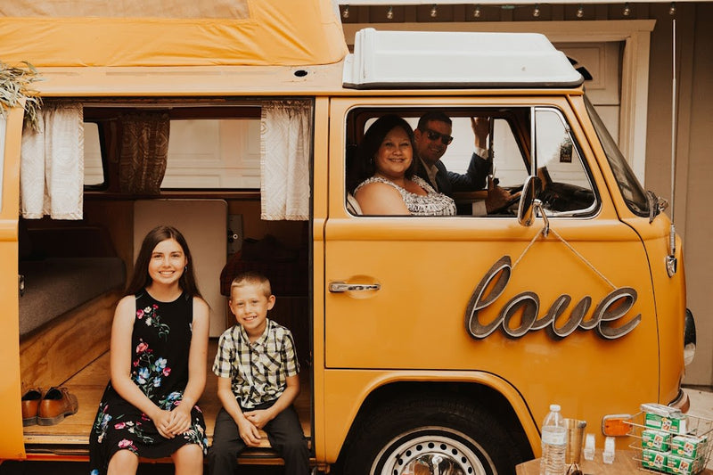 Family portrait with a vintage yellow Volkswagen rv rental. Two kids sitting in the open side, adults inside, 'love' sign. — photo 10