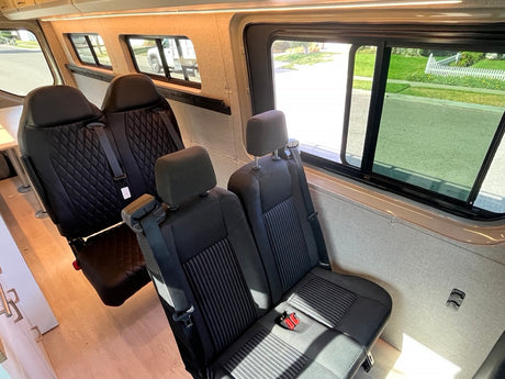 Spacious RV rental interior with comfy multiple-row seating, ideal for group travel & van life adventures.