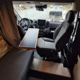 Interior of an rv rental, with the driver's cabin and a table visible. A rainy view can be seen through the windshield.