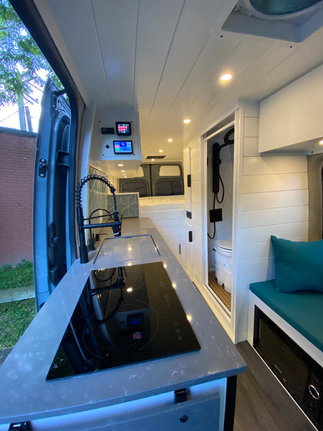 Explore a luxurious RV rental interior: sleek kitchen, compact bathroom, comfy bed, & smart controls for van life adventures.