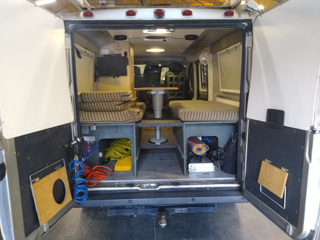 Inside an **RV rental** camper van, featuring a flexible interior with bench seating, convertible bed, table, and ample storage.