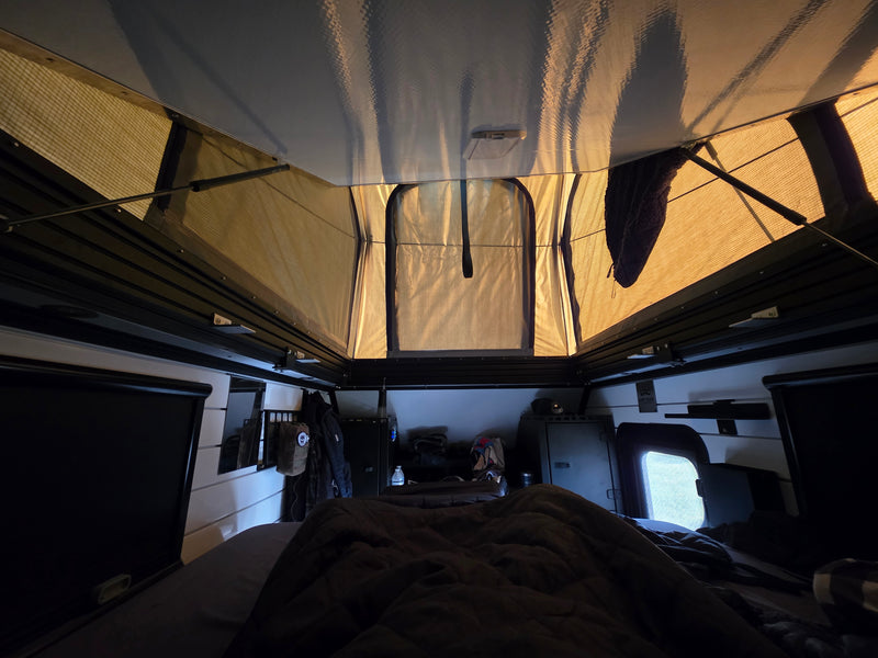 Inside an RV rental pop-top camper, a cozy sleeping area and storage are visible below the mesh windows and high ceiling. — photo 8