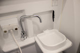 This RV rental features a compact white bathroom sink with a chrome faucet, hot/cold knobs, and pull-out sprayer.