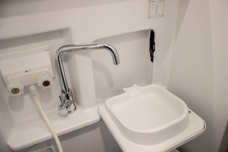 This RV rental features a compact white bathroom sink with a chrome faucet, hot/cold knobs, and pull-out sprayer.