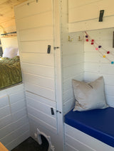 Explore this custom RV rental's cozy interior, featuring a bed, seating, and unique pet-friendly space.