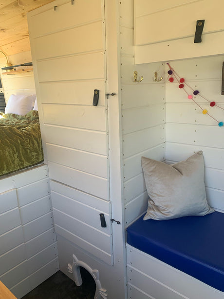 Explore this custom RV rental's cozy interior, featuring a bed, seating, and unique pet-friendly space.