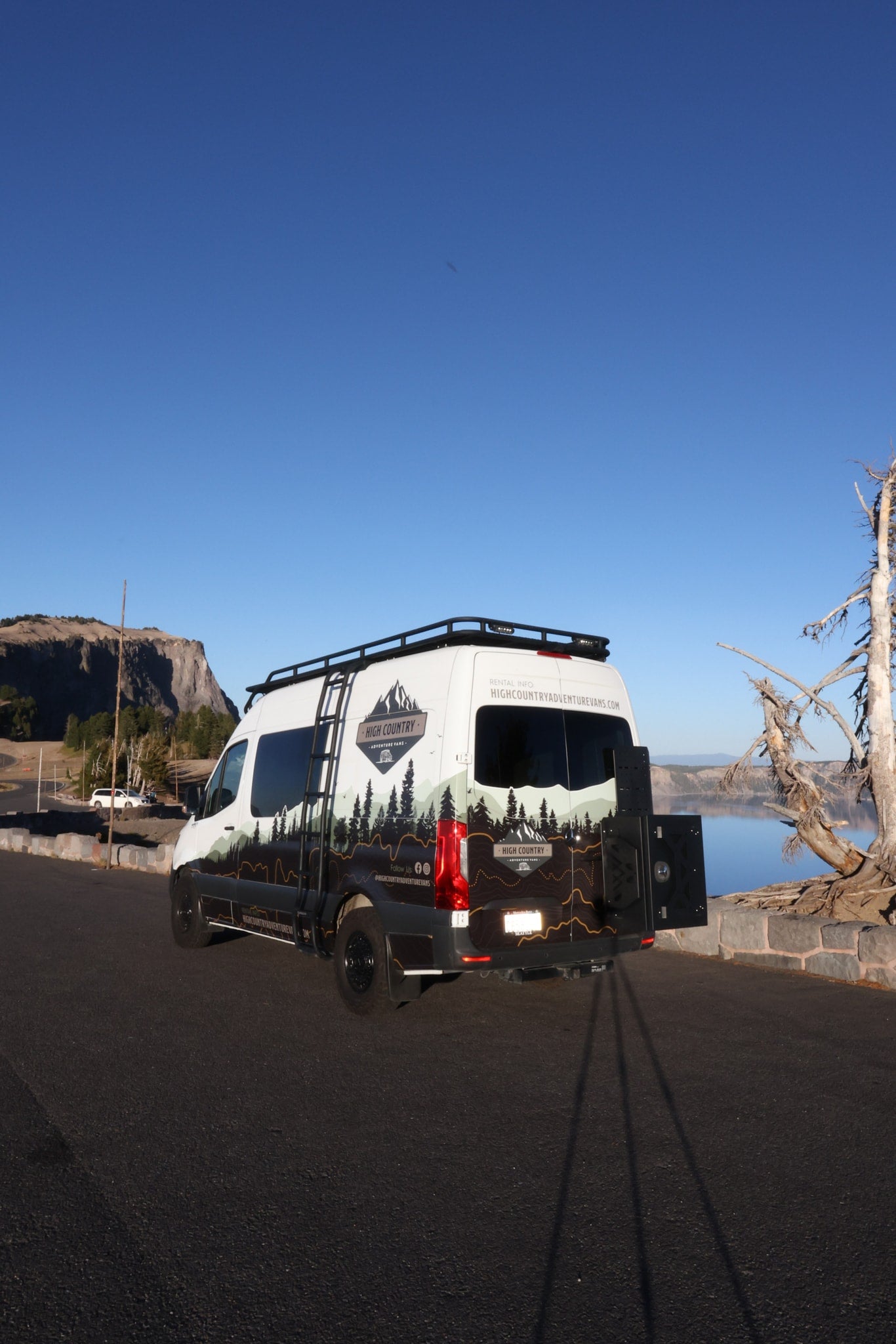 This High Country Adventure Vans RV rental, with unique mountain graphics, is parked at a scenic lake overlook. — photo 3