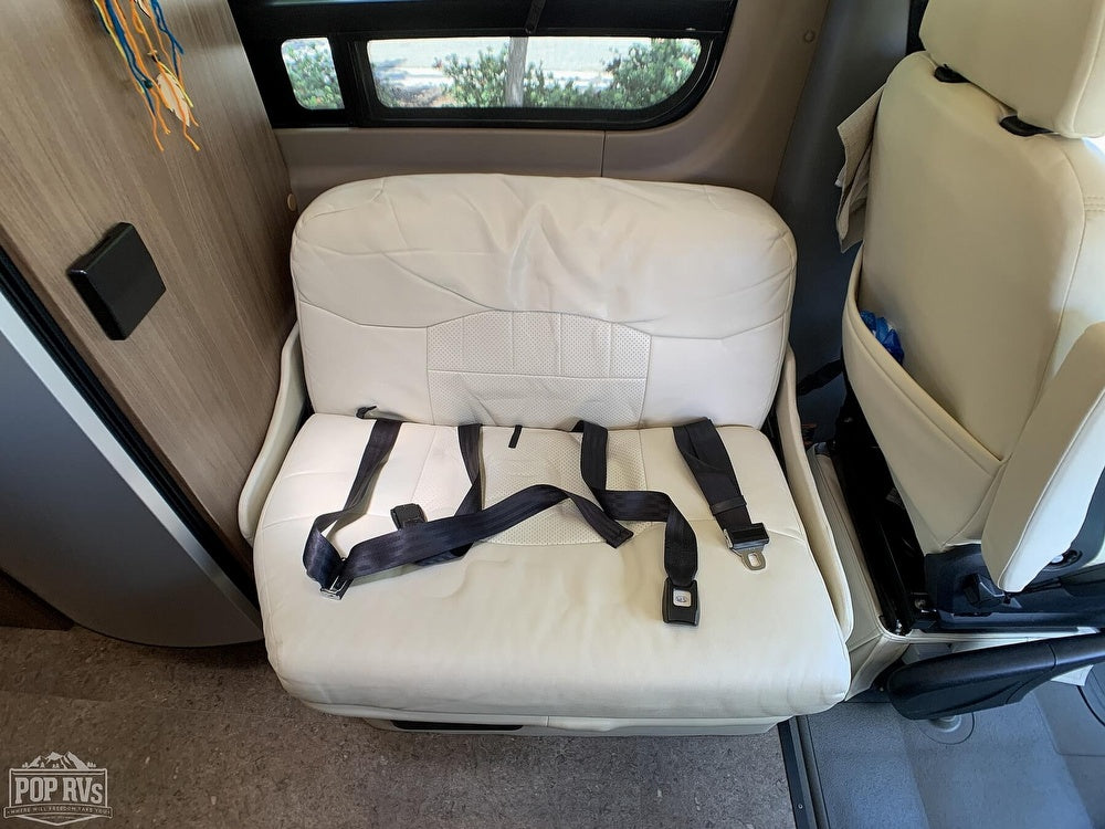 Cream auxiliary seat with black seatbelt inside an **RV rental**, ensuring passenger comfort and safety.
