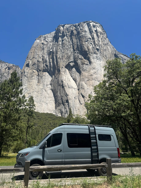 This grey camper van RV rental awaits adventure at Yosemite National Park, with El Capitan towering in the background.