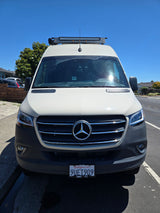 Front view of a white Mercedes-Benz Sprinter van, an ideal rv rental. Features a roof light bar. California plate 9UET909.