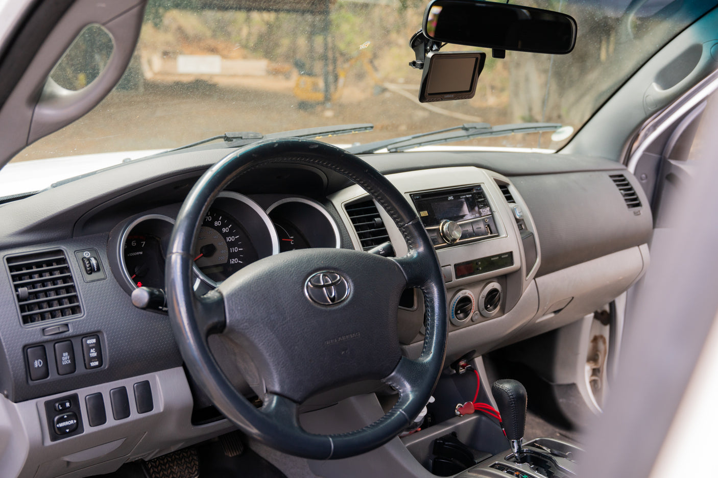 Dashboard and driver's view inside a Toyota truck, showing steering wheel, stereo, and dusty windshield. Ideal for an RV rental.
