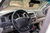 Dashboard and driver's view inside a Toyota truck, showing steering wheel, stereo, and dusty windshield. Ideal for an RV rental.