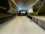 Spacious camper van interior for your next rv rental adventure. Features bed platform, overhead storage, and front cabin view.