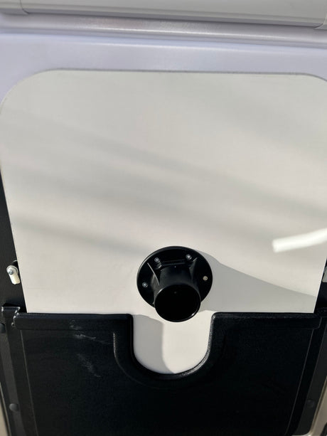 Black electrical power inlet on white RV rental side, ready for hookup. Essential for recreational vehicle power.