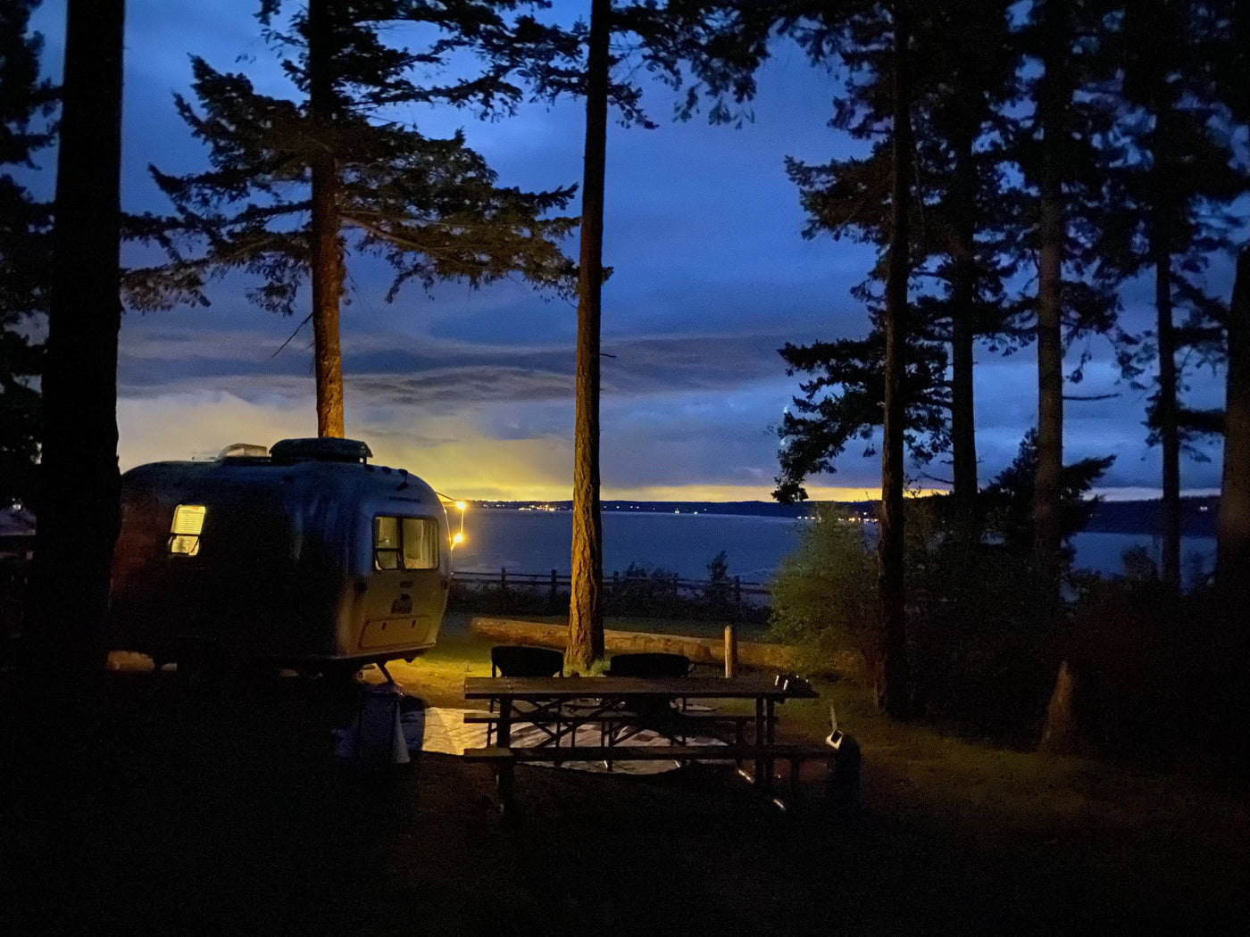 cloudy sky.|RV rental: A vintage trailer at a waterside campsite