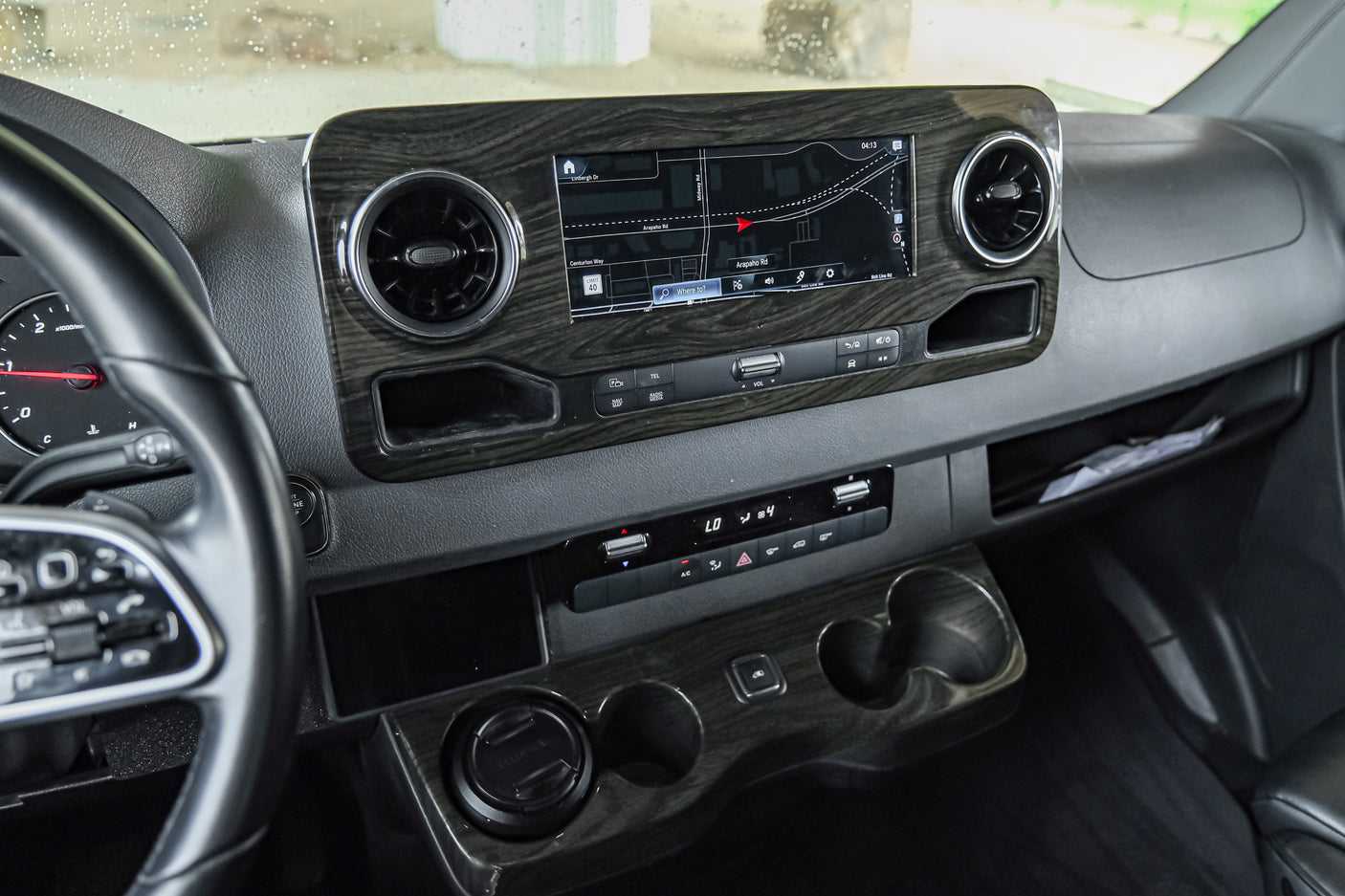 Detailed RV rental interior: modern dashboard with large navigation screen, climate controls, and wood trim.