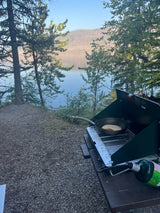 An RV rental adventure cooking a lakeside breakfast on a camping stove. Peaceful morning by the water.