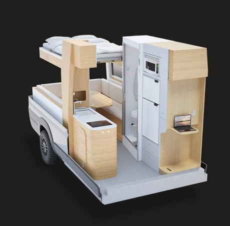A detailed view of a modular RV rental's interior, showcasing a compact kitchen, bed, bathroom, and laptop workstation.