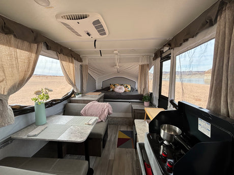 Inside a cozy rv rental, showing the dining area, bed, and kitchen with stunning desert and lake views.