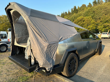 An electric Tesla Cybertruck with an attached overlanding tent setup, offering a modern RV rental alternative for adventures.