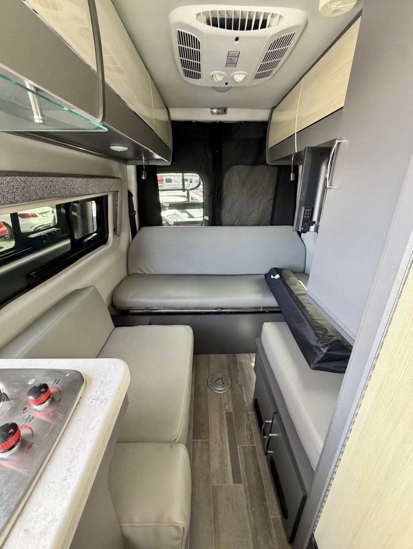 Explore this RV rental's camper van interior: a compact living area with kitchen, convertible seating, AC, and storage.