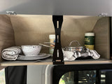 Organized RV rental cabinet, neatly stocked with essential kitchenware: plates, bowls, pots, pans, and towels.