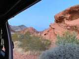 View from RV rental: striking red rocks and desert flora under a clear sky.