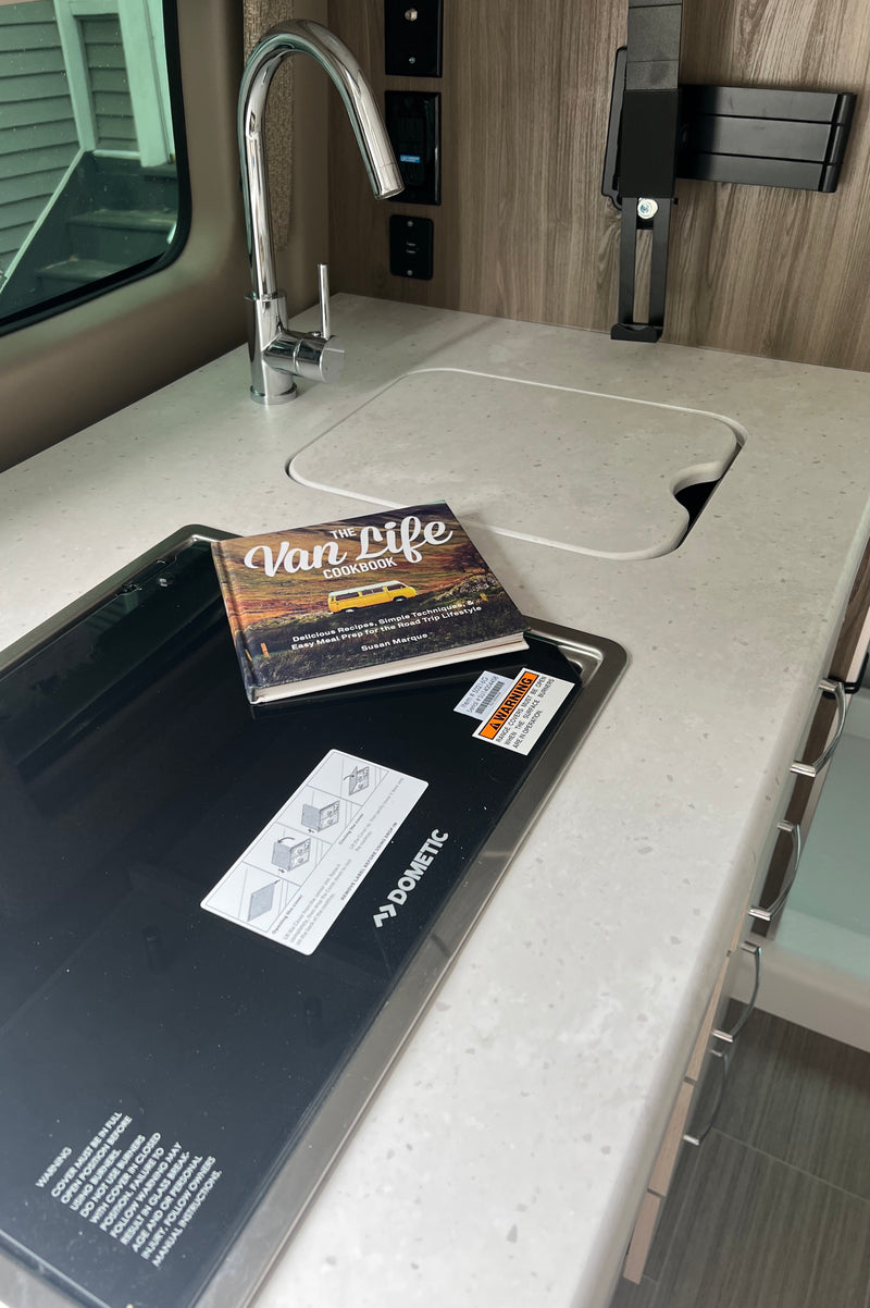 RV rental compact kitchen with sink, Dometic cooktop, and "The Van Life Cookbook" on the counter. — photo 19