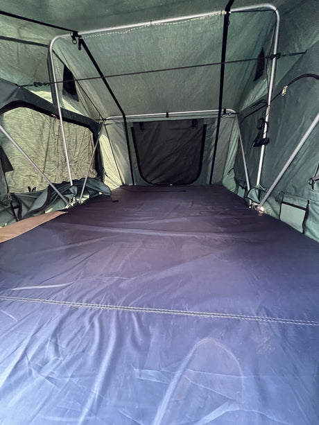 Spacious green rooftop tent interior with blue mattress, ideal for your next RV rental camping adventure.