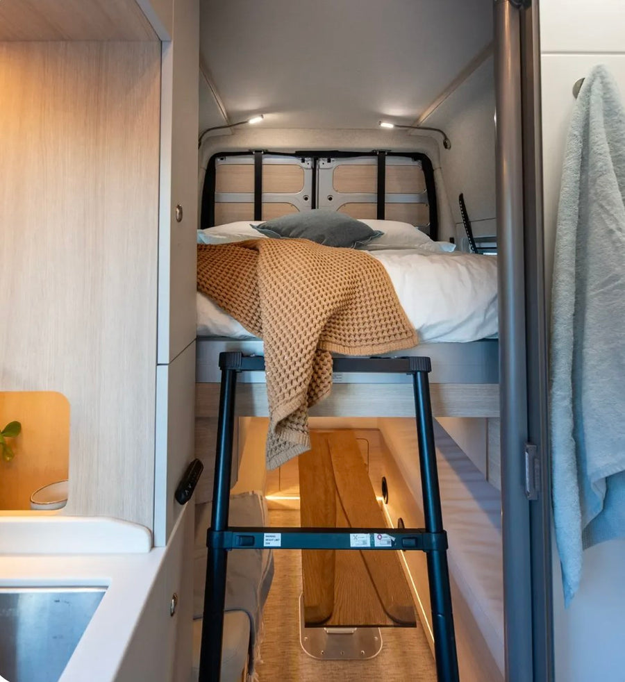 featuring a laptop on a light wood desk. Ideal for remote work while traveling.|Serene rv rental camper interior with open doors to a scenic lake and mountain view. Cushions and table ready for adventure.|Detailed RV rental interior floor plan showcasing precise dimensions (inches) of kitchen
