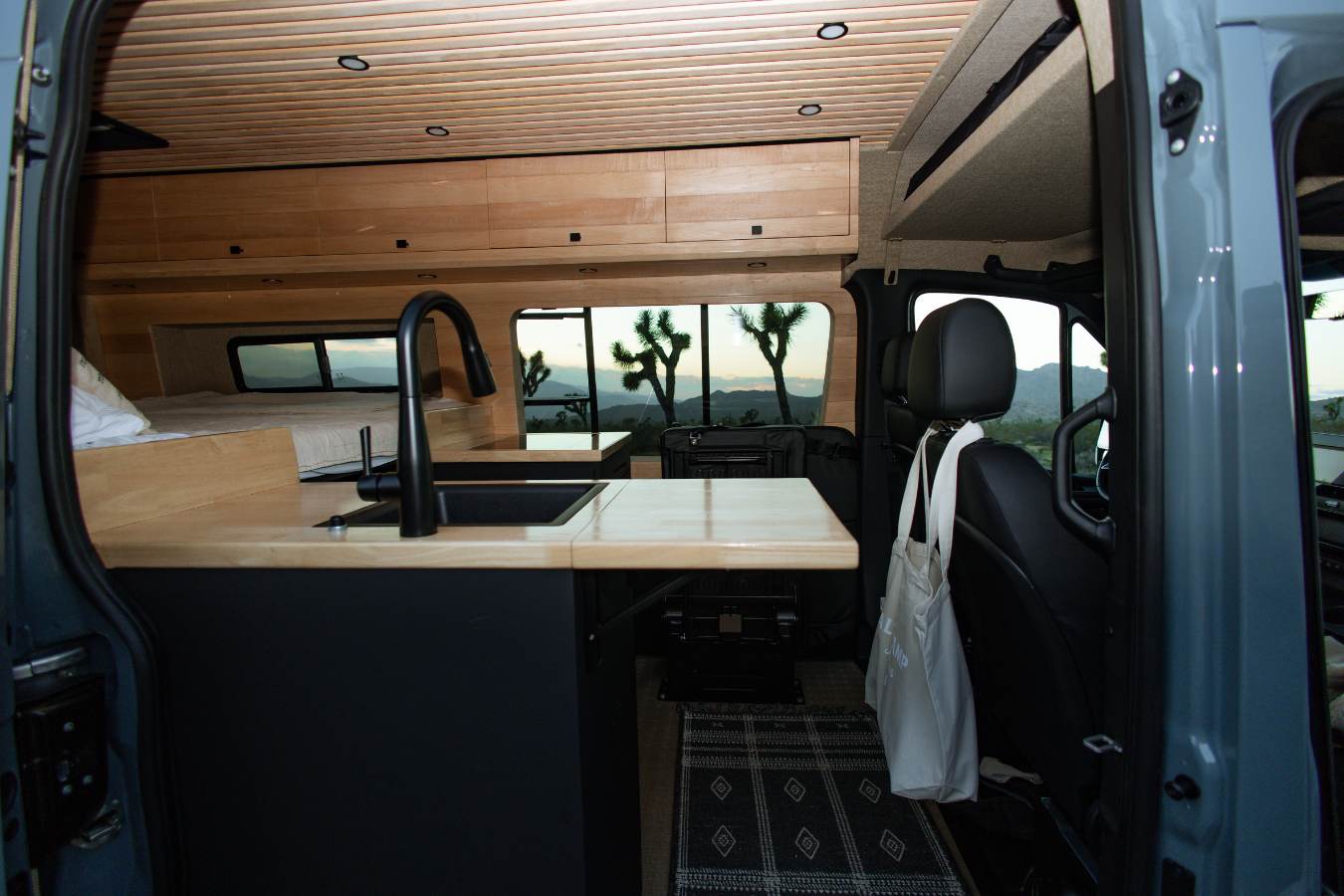 featuring two green C.C. Filson blankets and warm wooden finishes.|Explore with this robust Mercedes Sprinter RV rental — photo 8