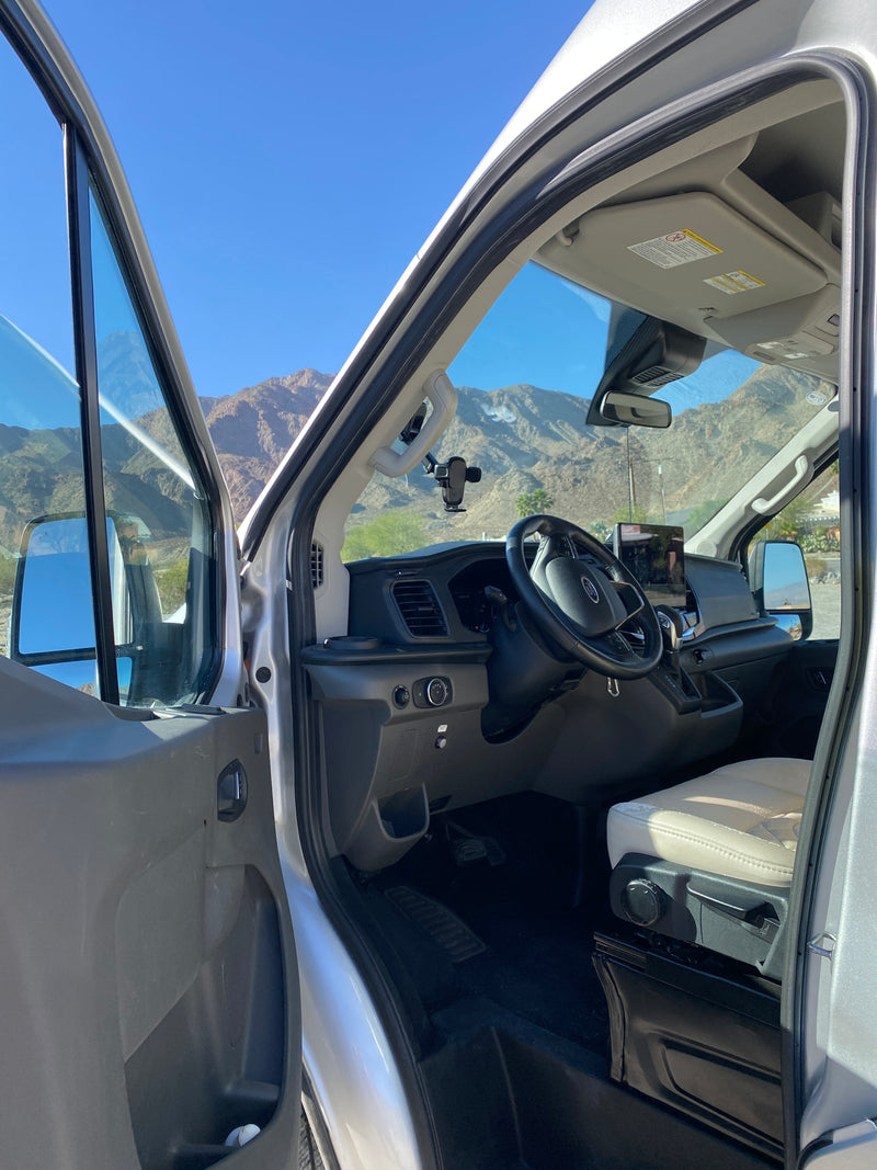 RV rental van interior: open door reveals driver's seat, dashboard, and scenic mountain views on a sunny day. — photo 9