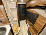 This RV rental showcases a compact interior with a full bathroom, kitchen sink, and versatile living/sleeping area.