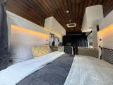 This rv rental's cozy van conversion features a full bed, custom kitchen, wooden ceiling, and practical LED lighting.