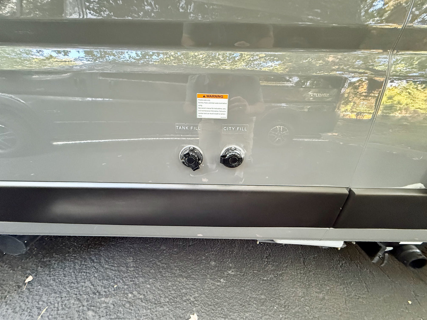 Close-up of an rv rental's side, featuring "TANK FILL" and "CITY FILL" water inlets with a warning for potable water.