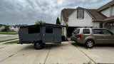 RV rental: A sleek grey camper trailer, hitched to an SUV in a driveway, ready for outdoor adventure.