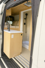 RV rental: Modern van interior features a compact kitchen, comfortable bed, and full shower, ideal for travel.