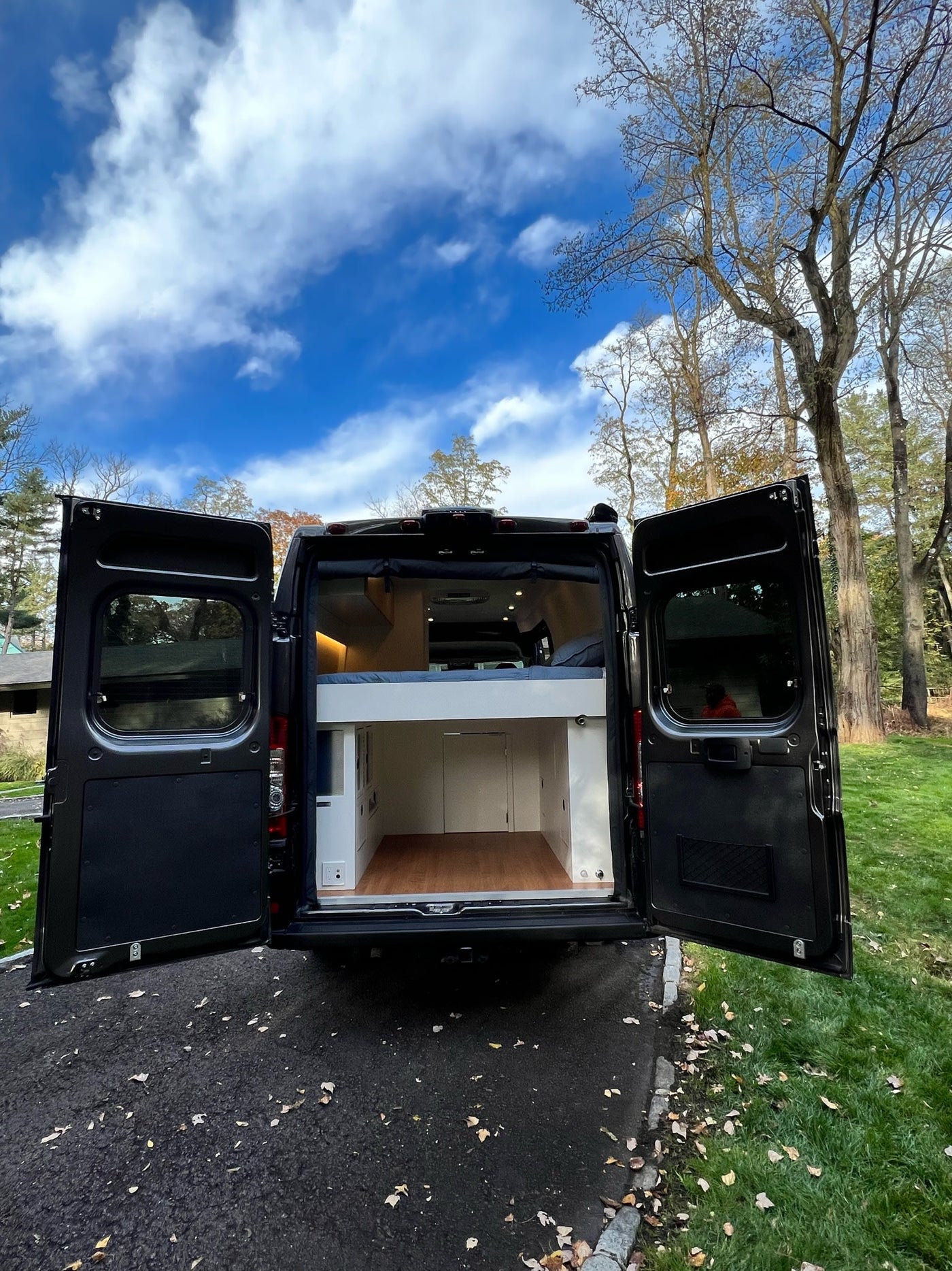  parked among vibrant autumn trees.|Explore this modern rv rental's interior! Features a compact kitchen with wood counter — photo 4