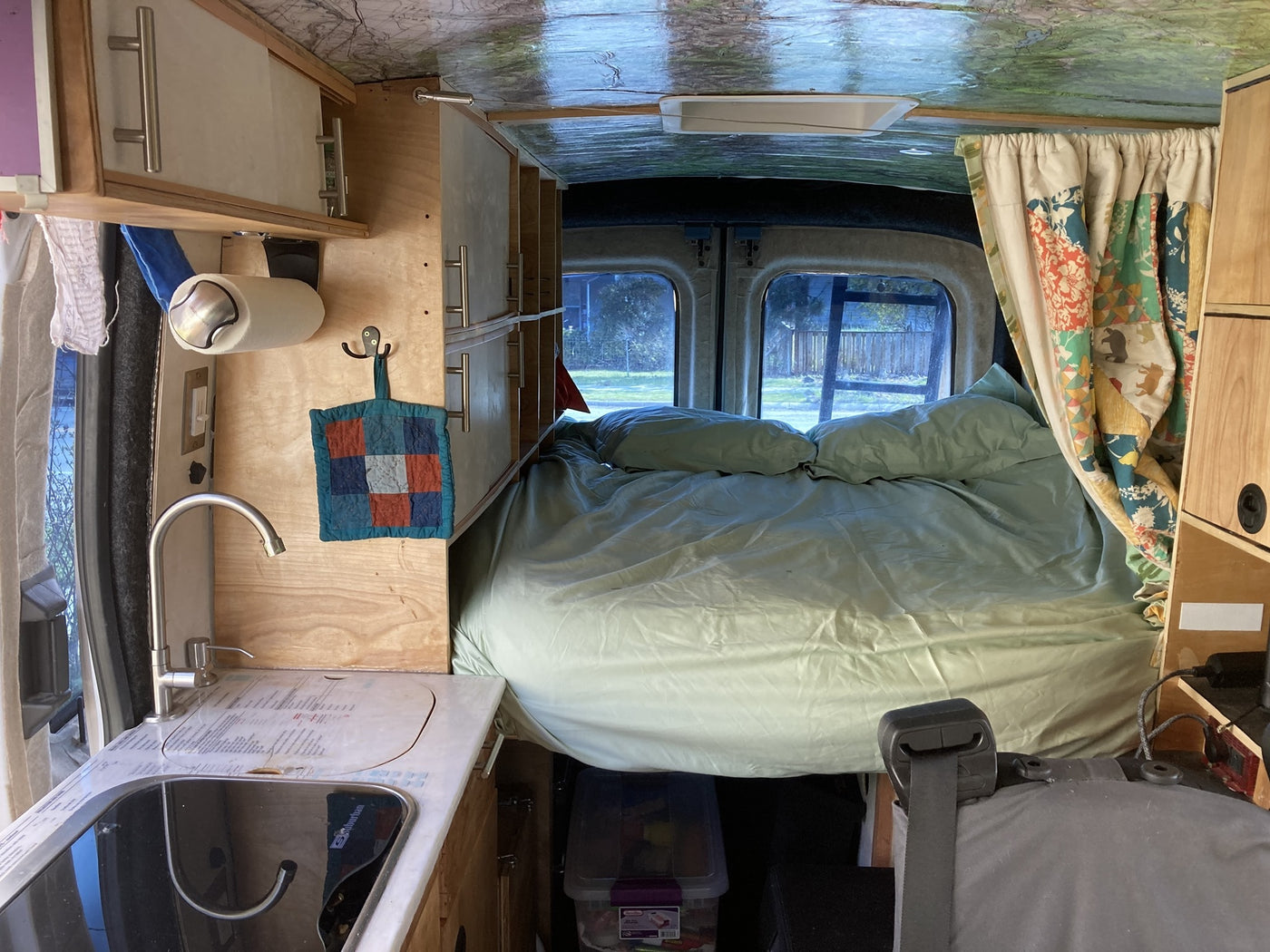 Experience a versatile RV rental: compact kitchen, comfortable bed, and overhead storage in this camper van interior. — photo 11